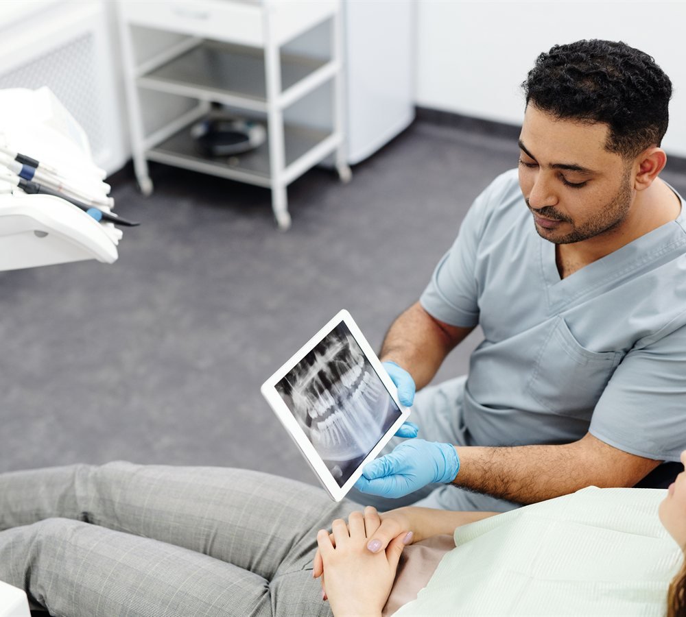 Periodontist reviewing dental imaging with a patient before an extraction